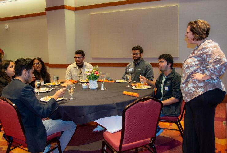 Michelle Seref (standing at right), Pamplin's interim assistant dean of outreach and student engagement, talks with students at the luncheon. The students include (clockwise from left) Anay Maheshwari, Sanjana Mehta, Isha Ghatule, Shubh Patel, Abhay Pai, and Sharmad Samant. Photo by Amanda Broome for Virginia Tech.
